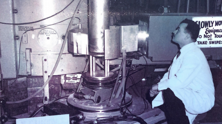 black and white photo of a man looking at a microscope
