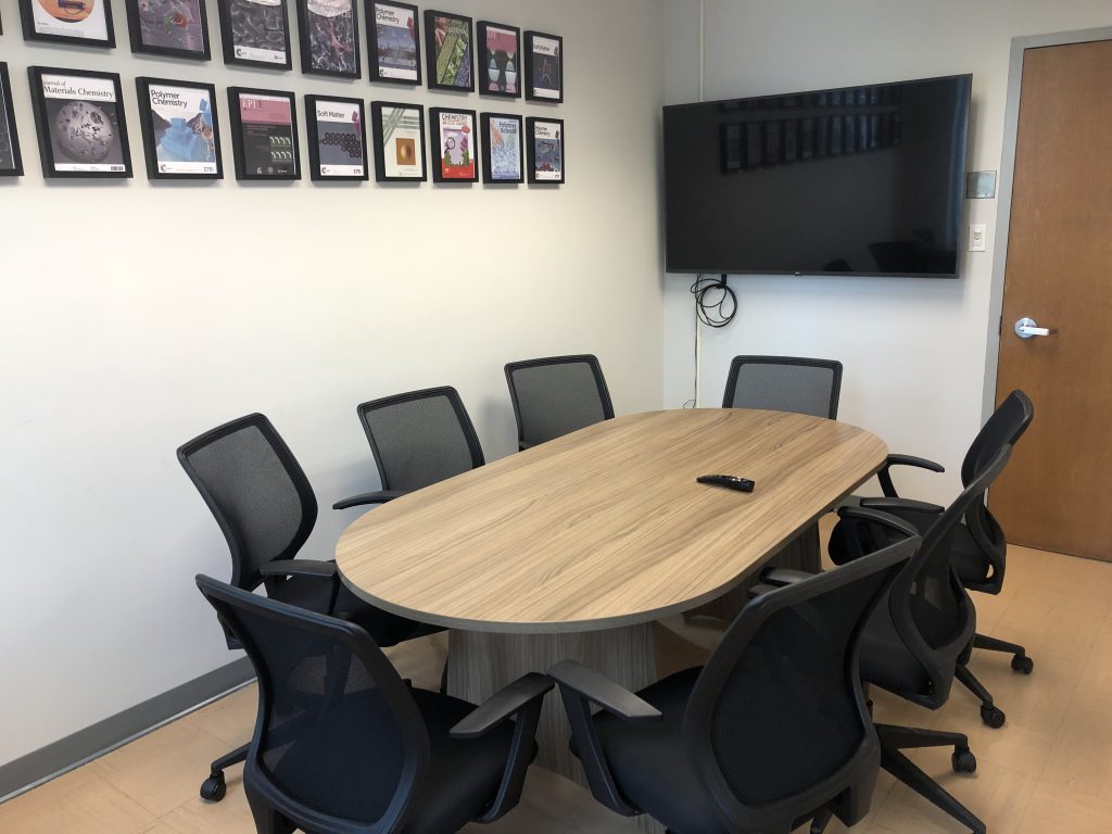 board table with chairs, tv screen and frames on the wall